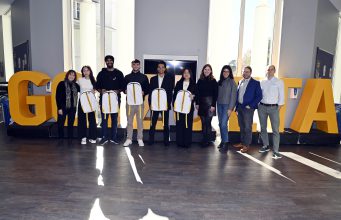 Team Charlie standing in front of Goizueta letters with Goizueta Faculty and UPS Judges