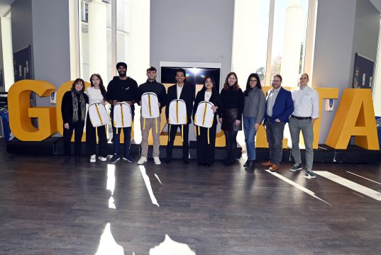 Team Charlie standing in front of Goizueta letters with Goizueta Faculty and UPS Judges